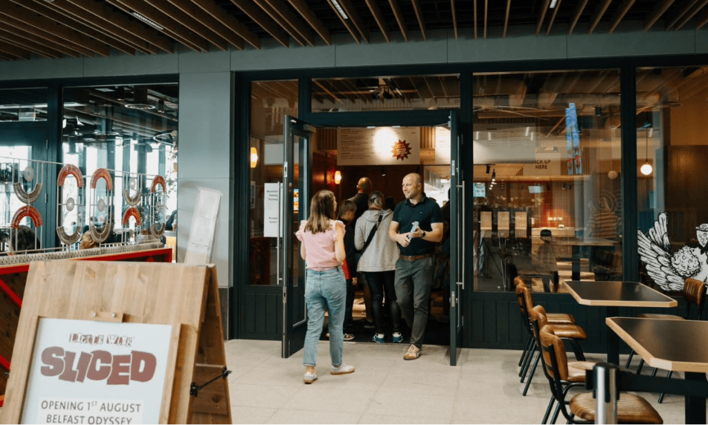 People walking into Little Wing Sliced, pizza shop in Odyssey Place